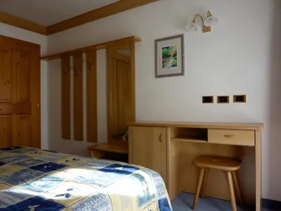 a bedroom with a bed and a desk and a table at Appartamenti Majon Sotroi in Campitello di Fassa