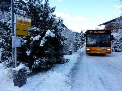 a bus is driving down a snow covered road at Appartamenti Majon Sotroi in Campitello di Fassa