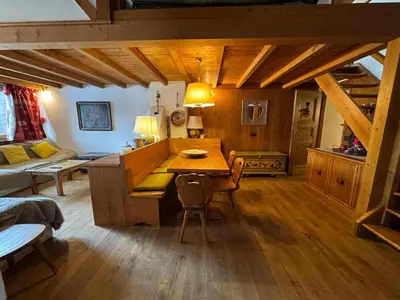 a living room with a wooden table and a kitchen at Alverà Apartment in Cortina dʼAmpezzo