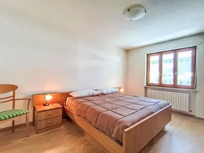 a bedroom with a bed and a chair and a window at Apartment Casa Dalpi by Interhome in Predazzo