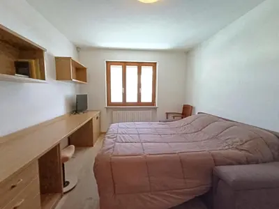 a bedroom with a bed and a desk and a window at Apartment Casa Dalpi by Interhome in Predazzo