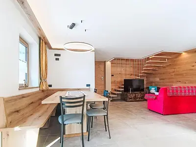 a wooden building in the snow with mountains in the background at Apartment Valeria by Interhome in Pera