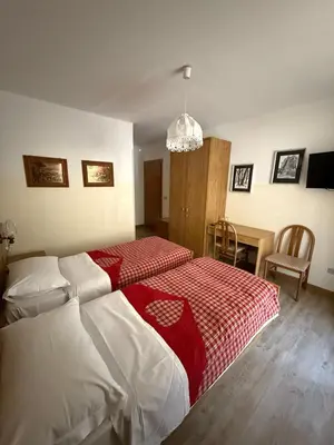 a bedroom with a bed with a red and white blanket at Garnì Defrancesco in Campitello di Fassa