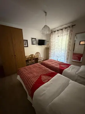 a hotel room with two beds and a table at Garnì Defrancesco in Campitello di Fassa