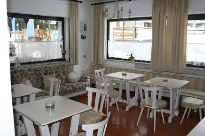 a restaurant with white tables and chairs and windows at Garnì Defrancesco in Campitello di Fassa