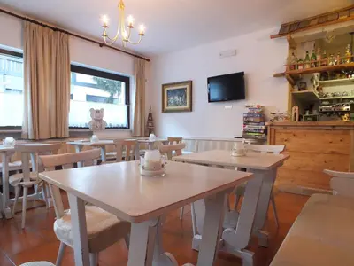 a dining room with tables and chairs and a tv at Garnì Defrancesco in Campitello di Fassa