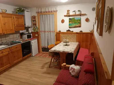 a kitchen with a table and a red couch at Trampolini House in Predazzo