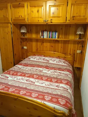 a bed in a room with wooden walls and wooden cabinets at Trampolini House in Predazzo