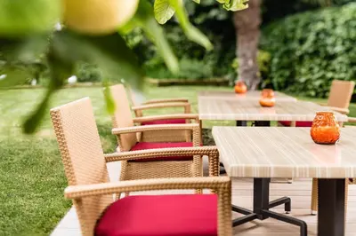 a row of tables and chairs with orange vases on them at Hotel Jardis in Lana