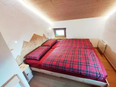 a bedroom with a red bed in a attic at Balcone sul Civetta in Colle Santa Lucia