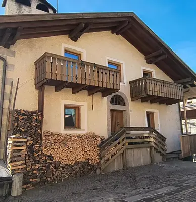 a house with a pile of fire wood on the side at Balcone sul Civetta in Colle Santa Lucia