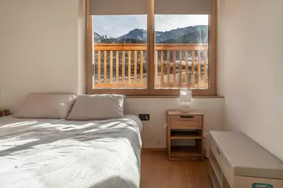 a bedroom with a bed and two windows with a balcony at Duplex Cermis in Cavalese