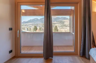 a room with a large window with a mountain view at Duplex Cermis in Cavalese