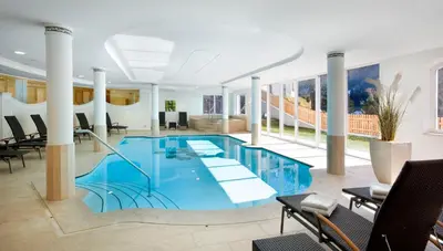 a large swimming pool with blue water in a building at Hotel Grones in Ortisei
