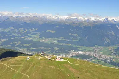 an aerial view of a green hill with mountains at Berghaus-Olymp Kronplatz in Brunico