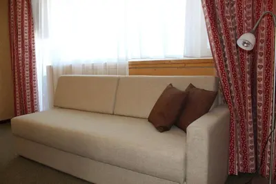 a couch with two pillows sitting in front of a window at Berghaus-Olymp Kronplatz in Brunico