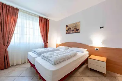 a bedroom with two beds and a window at Cesa Primula in Canazei