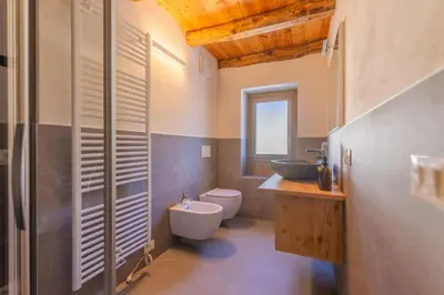 a bedroom with a bed with white sheets and wooden floors at Casa Vallazza - Val di Zoldo - Dolomites in Forno di Zoldo