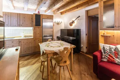 a kitchen with a table and a red couch at Casa Noce, tranquilla e immersa nella natura in Cortina dʼAmpezzo
