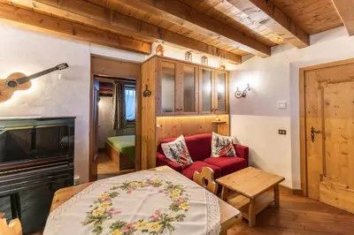 a room with a bed and a couch and a guitar at Casa Noce, tranquilla e immersa nella natura in Cortina dʼAmpezzo