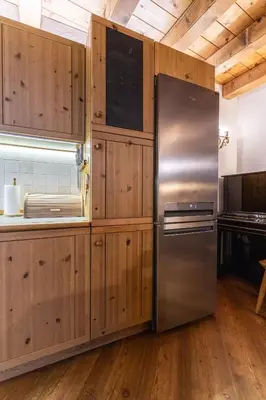 a stainless steel refrigerator in a kitchen with wooden cabinets at Casa Noce, tranquilla e immersa nella natura in Cortina dʼAmpezzo