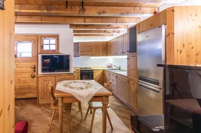 a kitchen with a table and a refrigerator at Casa Noce, tranquilla e immersa nella natura in Cortina dʼAmpezzo
