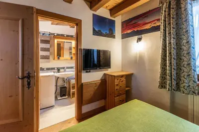 a small bathroom with a sink and a television at Casa Noce, tranquilla e immersa nella natura in Cortina dʼAmpezzo