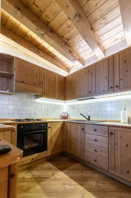 a kitchen with wooden cabinets and a stove top oven at Casa Noce, tranquilla e immersa nella natura in Cortina dʼAmpezzo