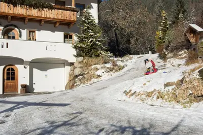 a person skiing down a snow covered road next to a building at Bärntalerhof in Falzes