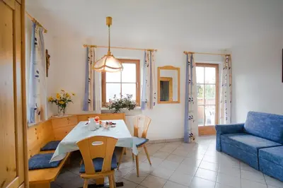 a living room with a table and a blue couch at Bärntalerhof in Falzes