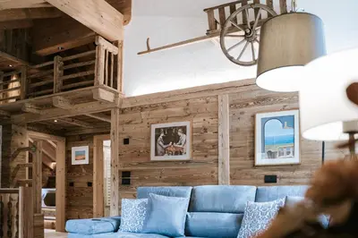 a living room with a blue couch and wooden walls at Chalet Mornà in San Martino in Badia