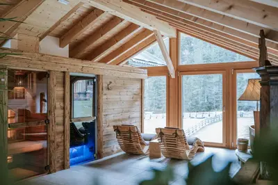 a room with rocking chairs and a large window at Chalet Mornà in San Martino in Badia