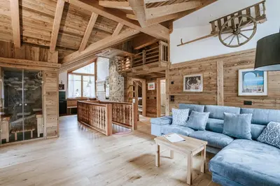 a living room with a blue couch and wooden walls at Chalet Mornà in San Martino in Badia