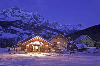 a log cabin in the snow at night with a mountain at Plaön Apartments in La Villa