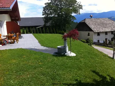 a yard with a building and a vase with flowers in it at Appartament Eichnerhof in Chienes