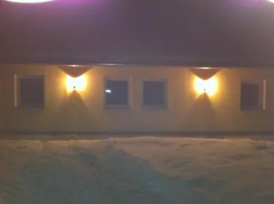 two lights on the side of a house with snow at Appartament Eichnerhof in Chienes