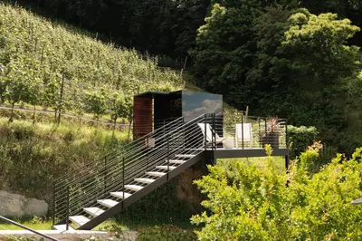 a resort with tables and umbrellas on a hill at Weingut Pratenberg in Merano