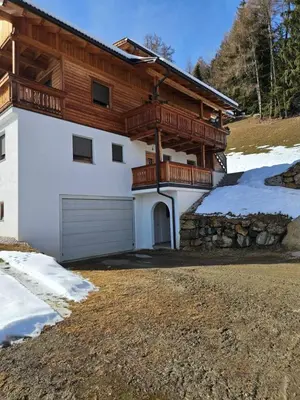 a house with a wooden balcony and a garage at Urlaub auf den Bauernhof Brunnerhof in Floronzo