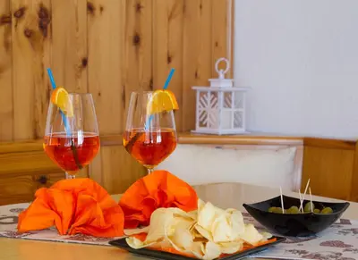 two glasses of wine and a bowl of food on a table at Camping Castelpietra in Fiera di Primiero