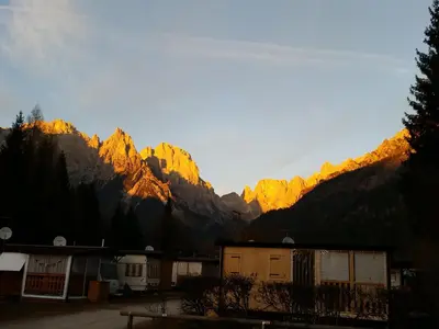 a view of the mountains with the sun shining on them at Camping Castelpietra in Fiera di Primiero