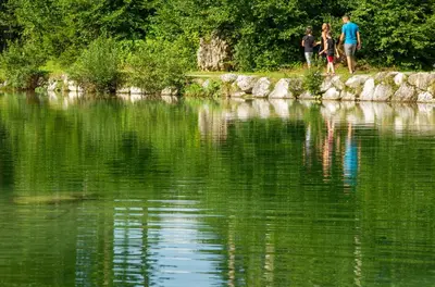two people walking on the shore of a body of water at Camping Castelpietra in Fiera di Primiero
