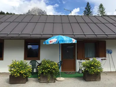 a house with an umbrella in front of it at Camping Castelpietra in Fiera di Primiero