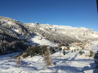 a snow covered mountain with a town in the distance at Garni Baita in San Cassiano