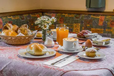 a table with a breakfast of pastries and orange juice at Garni Baita in San Cassiano