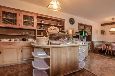 a kitchen with wooden cabinets and a counter with stools at Garni Baita in San Cassiano