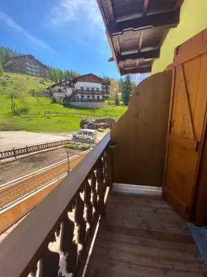a balcony with a door and a view of a house at Garni al Barance in Selva di Cadore