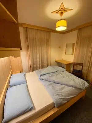 a large bed in a room with a light at Garni al Barance in Selva di Cadore