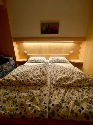 a bed with a comforter on it in a bedroom at Garni al Barance in Selva di Cadore