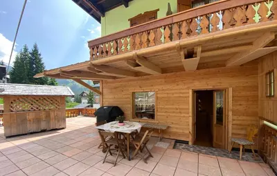 a wooden patio with a table and a balcony at Garni al Barance in Selva di Cadore