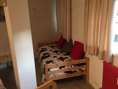 a small bedroom with a bed with red pillows at Casa Laurino In Centro A Bolzano in Bolzano